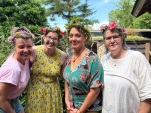 Het team van Kinderopvang Kwibus in de tuin met bloemenkransen.